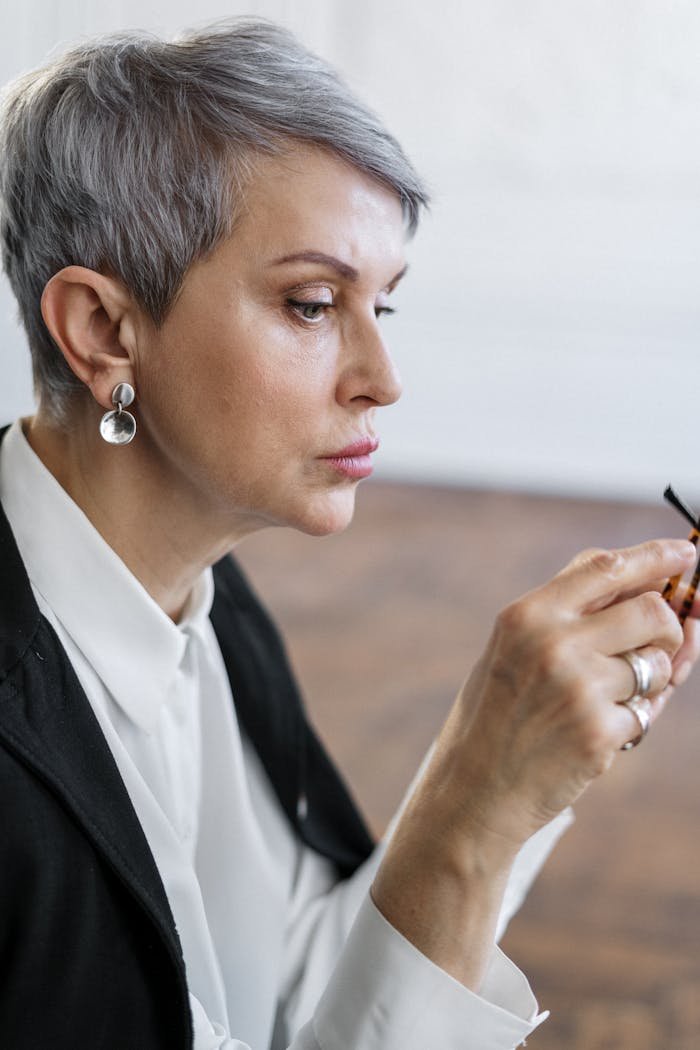 A thoughtful woman with short hair holding a pen in contemplation indoors.