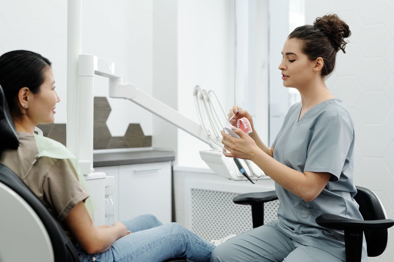 Dentist explaining dental care with model to patient in clinic setting